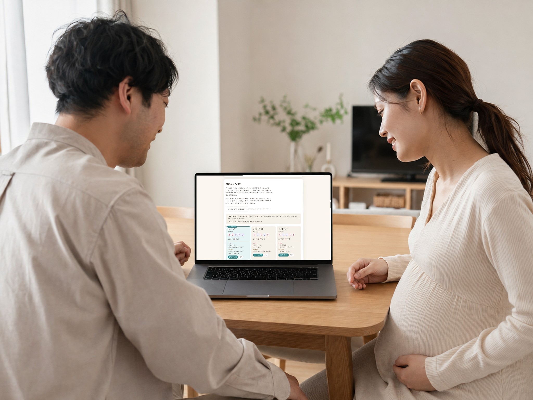 自宅のダイニングで夫婦がノートパソコンの「なまえのたね」を一緒に見ながら名前を相談している