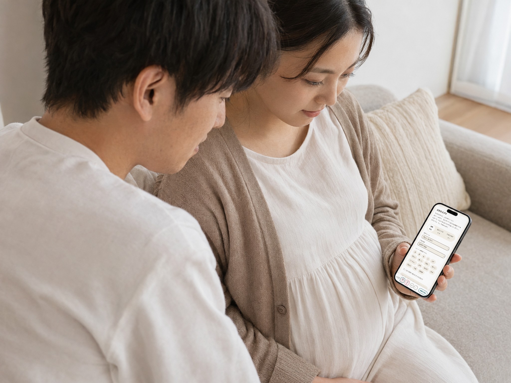 ソファに座った夫婦が、スマートフォンの「なまえのたね」で名前をさがしている