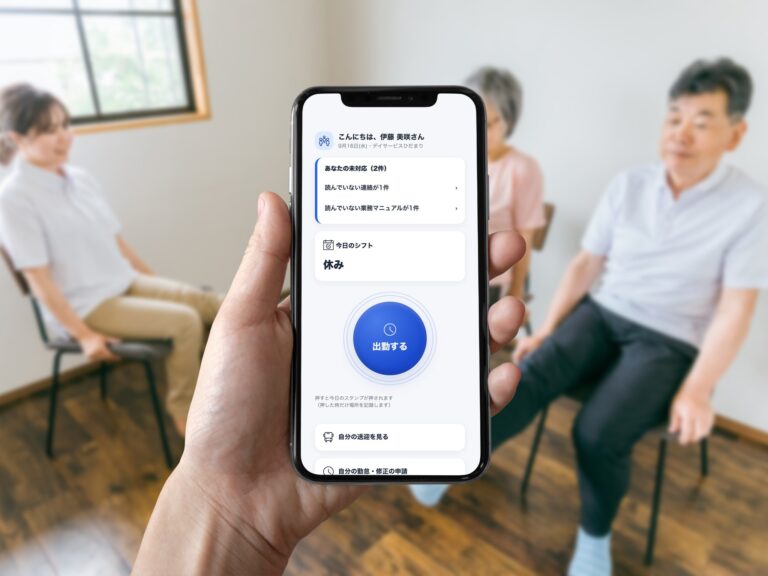 デイサービスで椅子体操をする職員と利用者を背景に、スマホに表示したWORKERS PADの「出勤する」ボタン